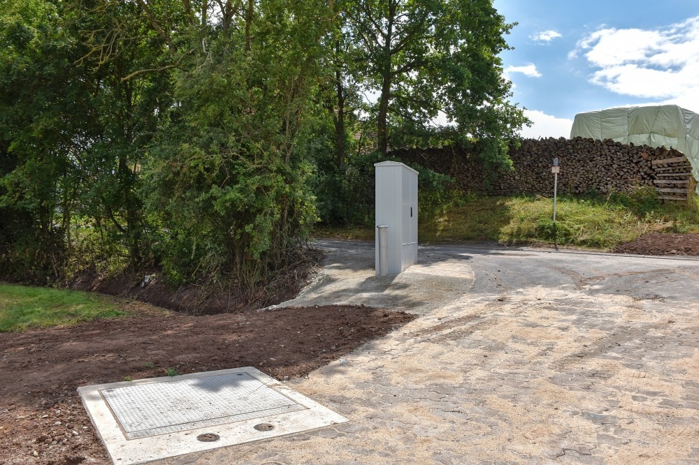 Die Stadt Feuchtwangen hat eine moderne Abwasserinfrastruktur im Ortsteil Herrnschallbach geschaffen. Zu sehen ist im Vordergrund der Schacht zum neuen unterirdischen Abwasserpumpwerk, dazu im Hintergrund der neue Schaltschrank.